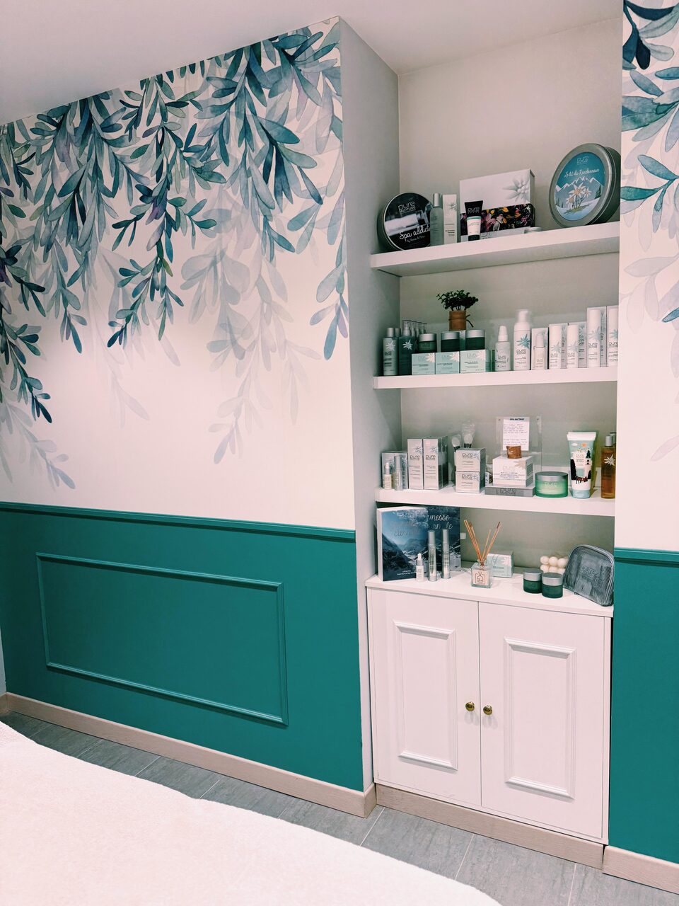 L'espace boutique devant la fresque de feuillage et les boiseries vert d'eau
